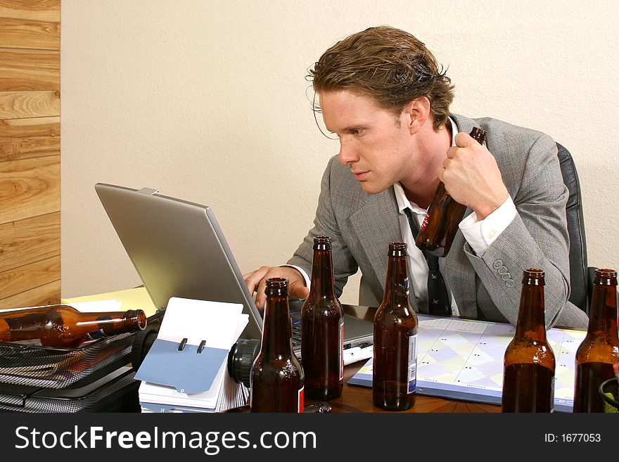 Business man at desk with empty beer bottles. Business man at desk with empty beer bottles.