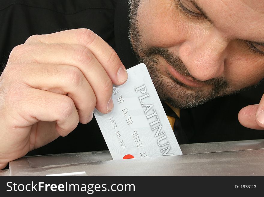 Close up of fourty something man placing credit card into paper shredder.