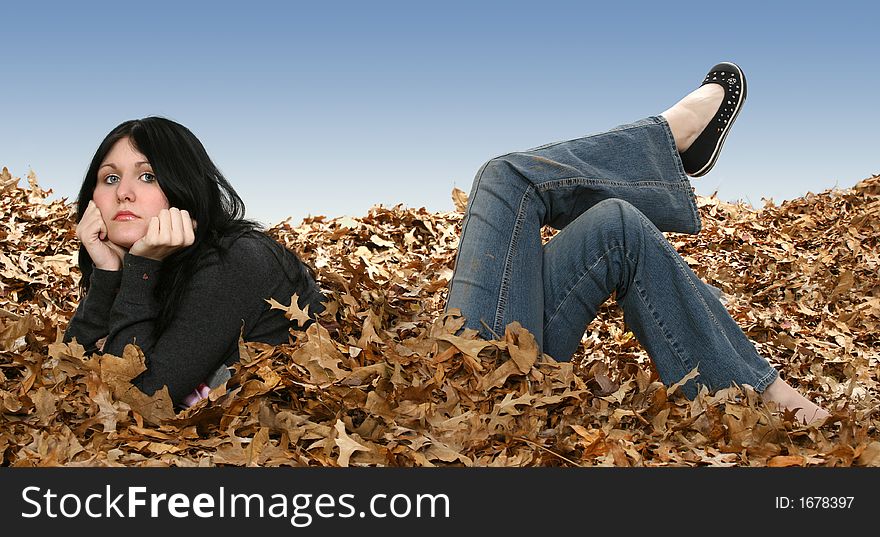 Beautiful teen girl laying in leaves with legs on backwards. Beautiful teen girl laying in leaves with legs on backwards.