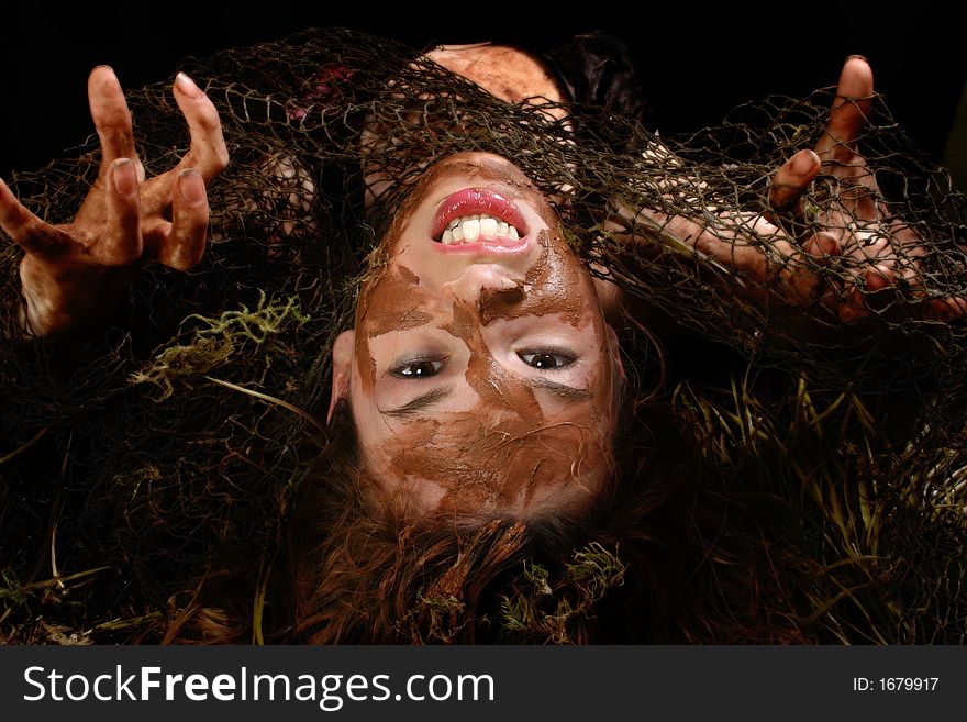 Beautiful Hispanic woman covered in mud, moss and fishnet over black. Beautiful Hispanic woman covered in mud, moss and fishnet over black.