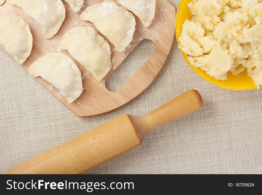 Raw dumplings, rolling pin and bowl with potato. Raw dumplings, rolling pin and bowl with potato