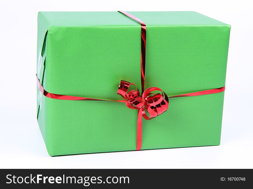 Gift in green wrapping with a red bow on white background