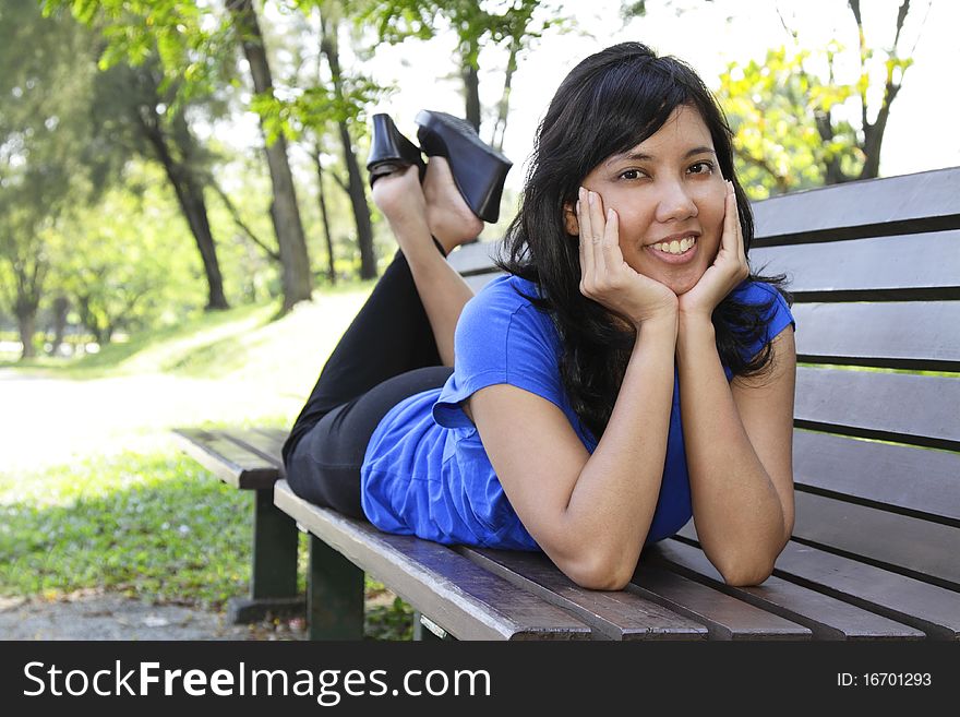 An Asian woman lying on a bench. An Asian woman lying on a bench