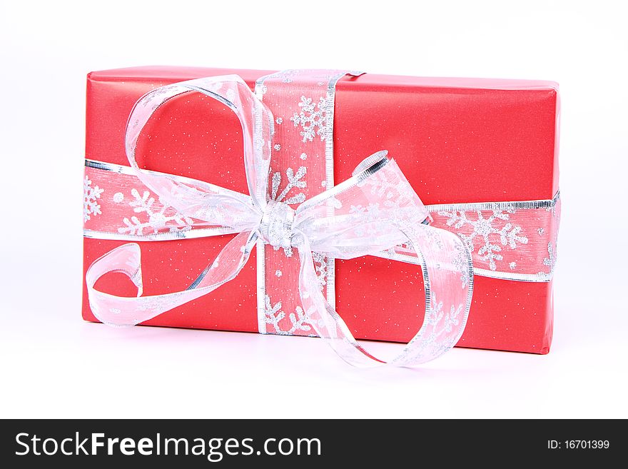 Gift in red wrapping with silver bow on white background