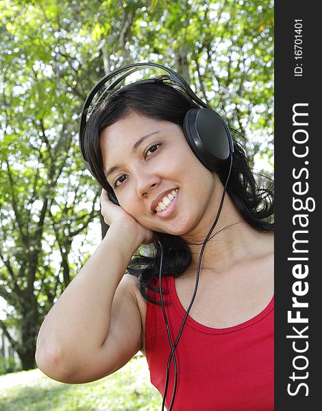 An Asian woman listening to music on headphones