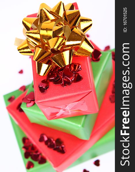 Gifts in green and red wrapping with a golden bow decorated with heart shaped confetti. Gifts in green and red wrapping with a golden bow decorated with heart shaped confetti