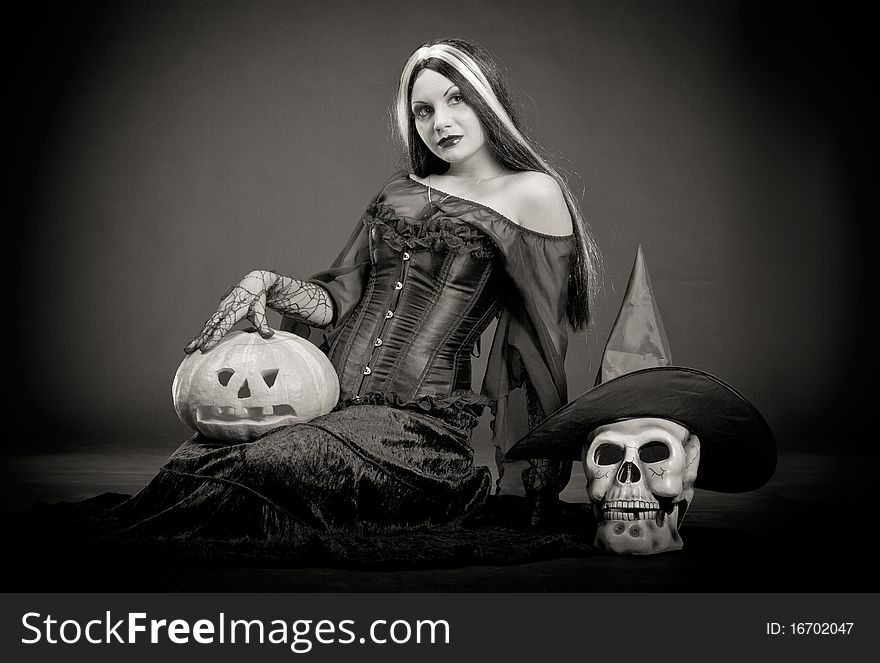 Halloween witch with a skull and pumpkin. Black and white