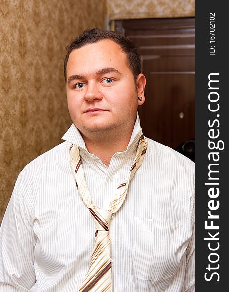 Indoors portrait of a young man wearing shirt with unfastened necktie
