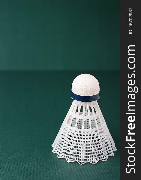 A white synthetic badminton shuttlecock on a green background.