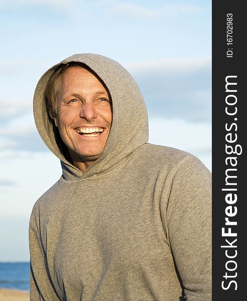 Happy laughing man in his forties wearing a grey hooded top.