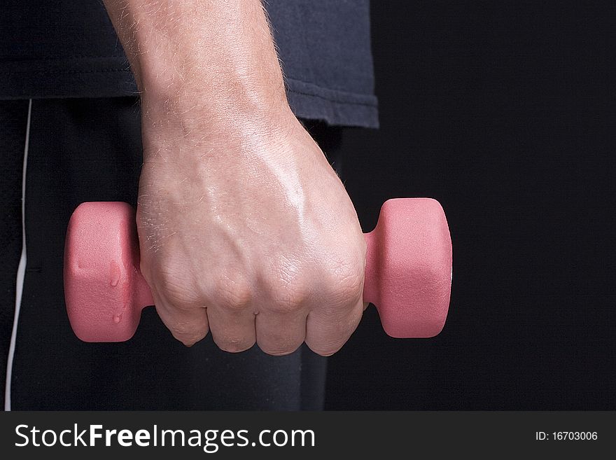 Human hand holding a pink dumbbell on a black background. Human hand holding a pink dumbbell on a black background.