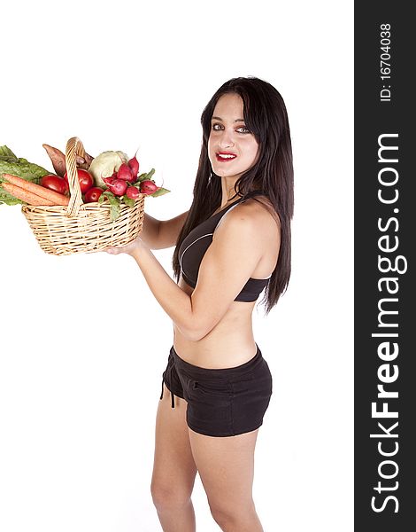 A woman in fitness attire is holding a basket of vegetables. A woman in fitness attire is holding a basket of vegetables.