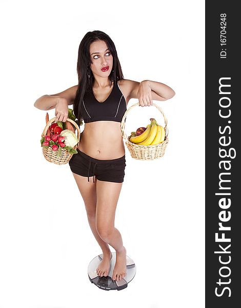 A woman is standing on the scales holding fruit and vegetables. A woman is standing on the scales holding fruit and vegetables.