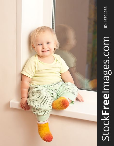 Adorable girl sitting on the window sill