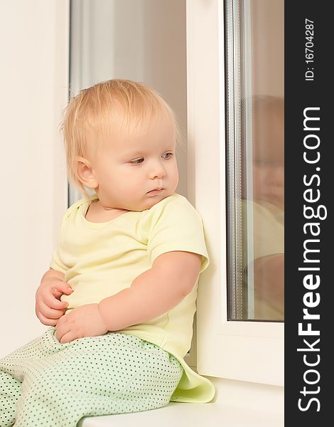 Adorable toddler girl sitting on the window sill look outside. Adorable toddler girl sitting on the window sill look outside