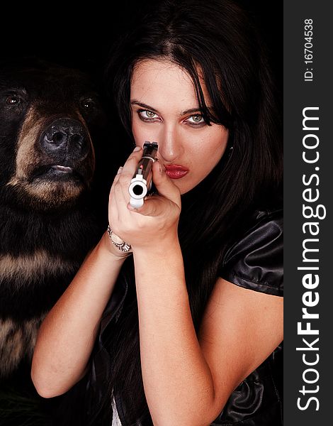 A woman is holding a gun by a black bear. A woman is holding a gun by a black bear.