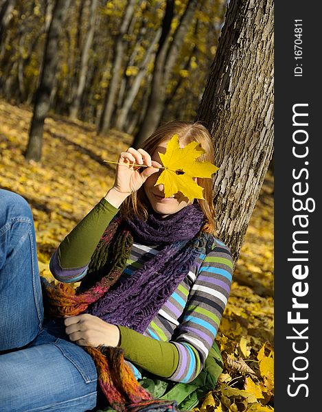 Woman was leaning against a tree, hiding behind the yellow leaf. Woman was leaning against a tree, hiding behind the yellow leaf