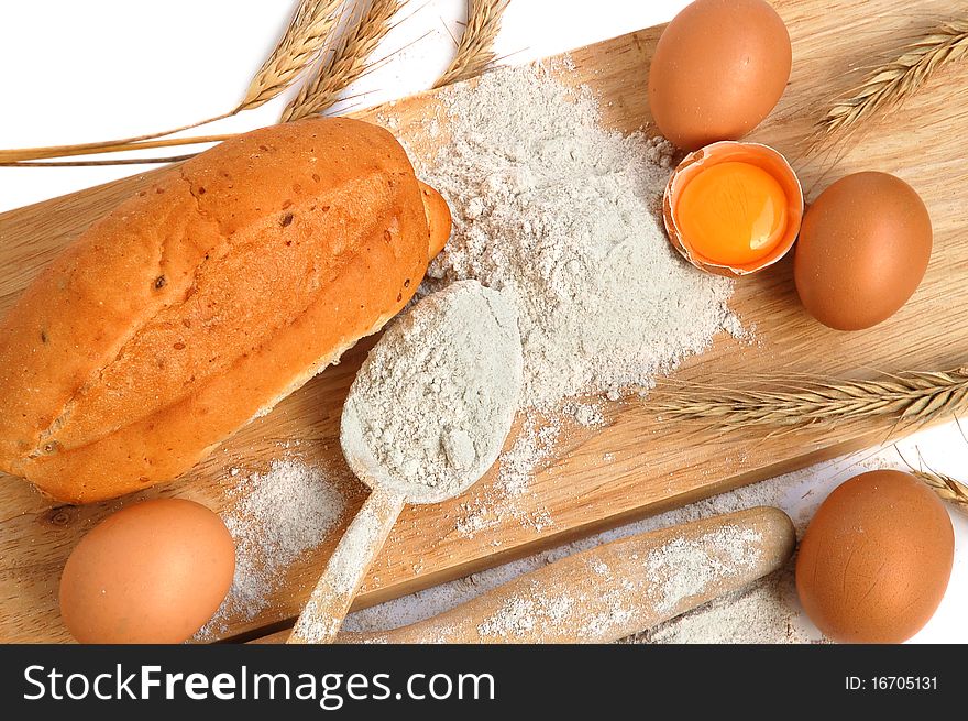 Still life of bread, eggs, cereas, flour and kitchen tools on a wooden board. Still life of bread, eggs, cereas, flour and kitchen tools on a wooden board