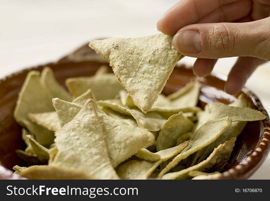 Mexican nopal made nachos seen close up while a woman hand grabs one. Mexican nopal made nachos seen close up while a woman hand grabs one