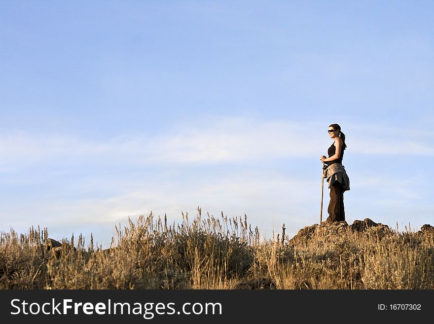 A young woman out for a hike in the mountains stops to enjoy the view from the top.