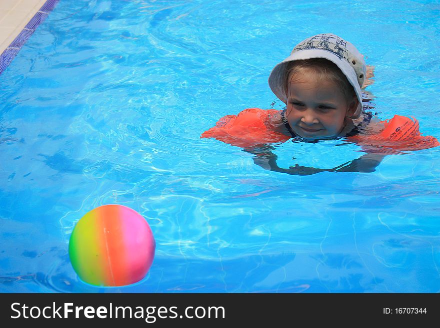 Girl swimming in armlets in a pool with a ball. Girl swimming in armlets in a pool with a ball