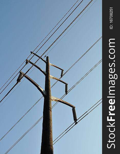 A single wood electrical pole against a blue sky. A single wood electrical pole against a blue sky