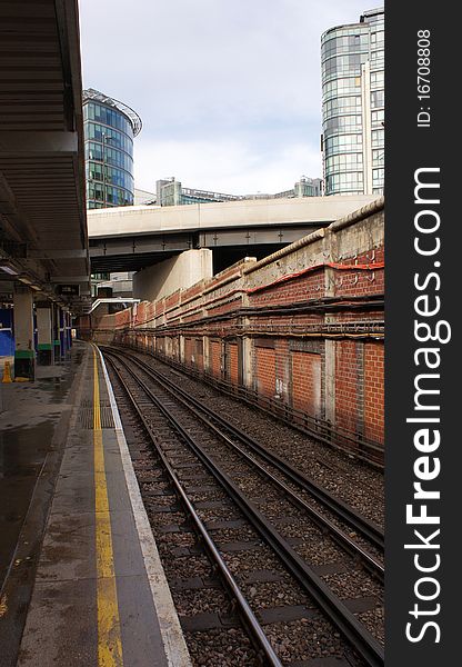 The tracks of the underground in london. this stop is on the surface and can be seen in the background the buildings of the city. The tracks of the underground in london. this stop is on the surface and can be seen in the background the buildings of the city.