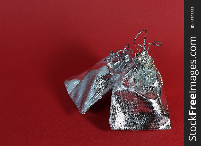 Packaging made from silver fabric for jewelry on a red background. Packaging made from silver fabric for jewelry on a red background