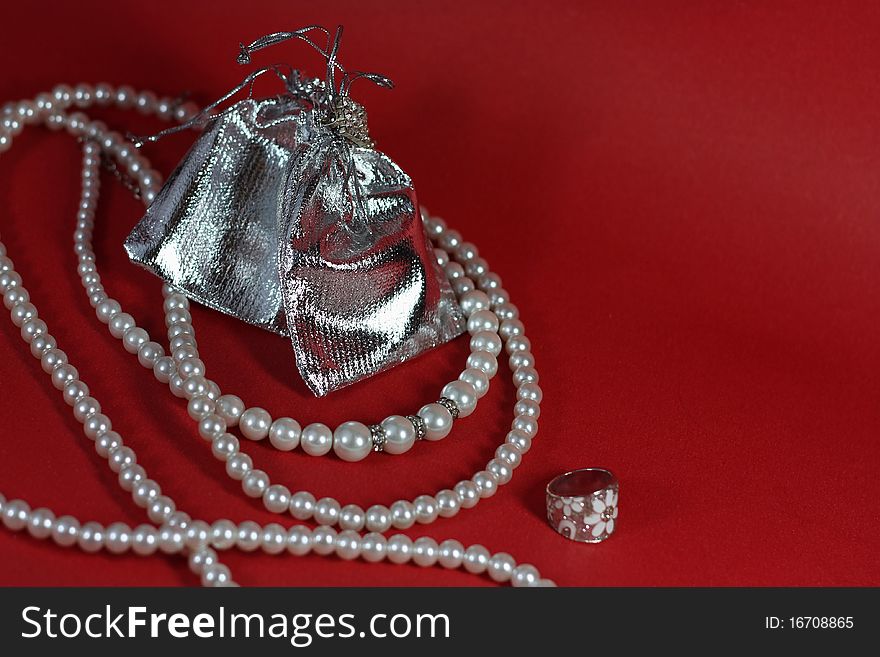 Still Life with pearls and silver jewelry on a red background