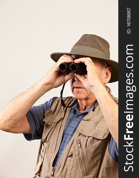 Mature man wearing hat and vest looking through binoculars. Mature man wearing hat and vest looking through binoculars.