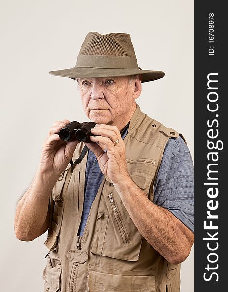 Mature man wearing hat and vest and holding binoculars. Mature man wearing hat and vest and holding binoculars.