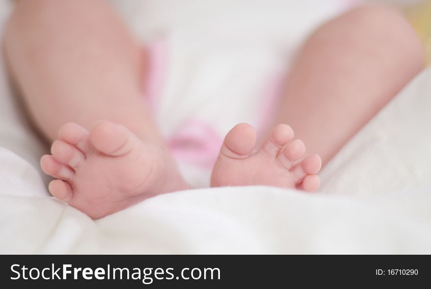 Legs of the baby on a white bedspread.