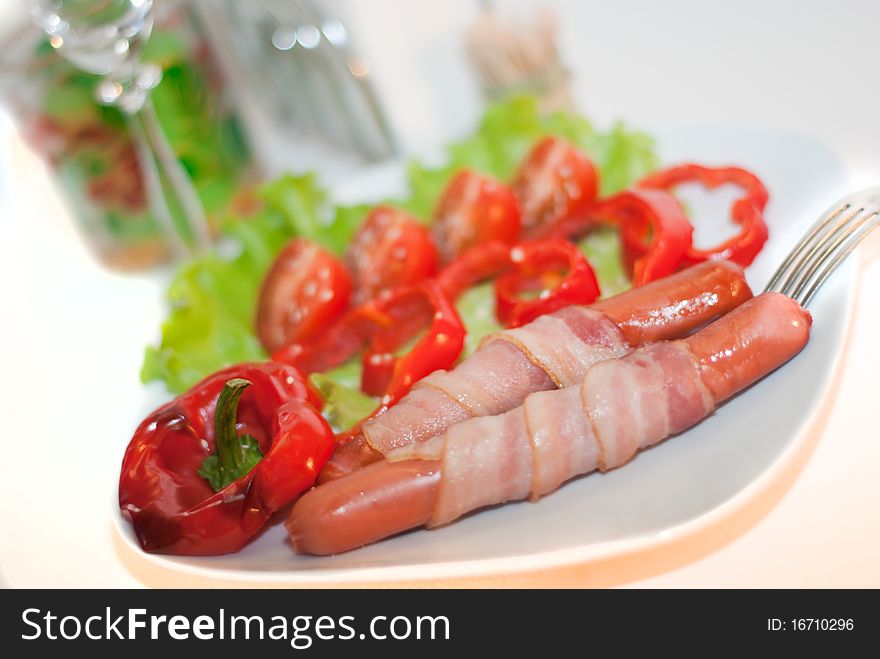 Grilled sausages with becon and vegetables on the plate