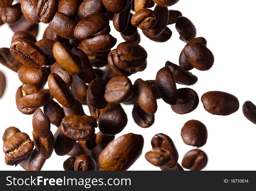 Falling grain roasted coffee on the side of a white background, photographed with a shallow depth of field. Falling grain roasted coffee on the side of a white background, photographed with a shallow depth of field