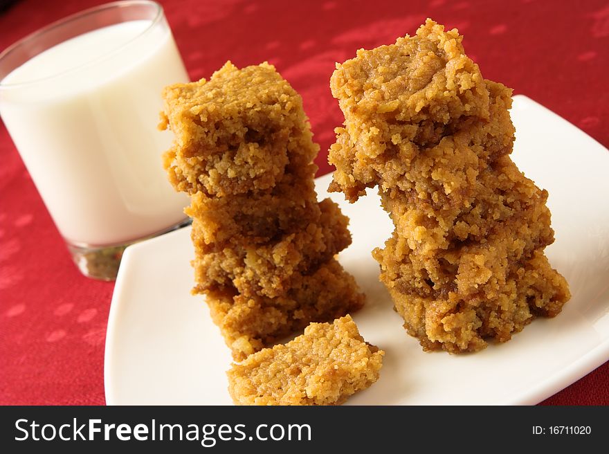 Glass of milk with two stacks of ginger shortbread biscuits.