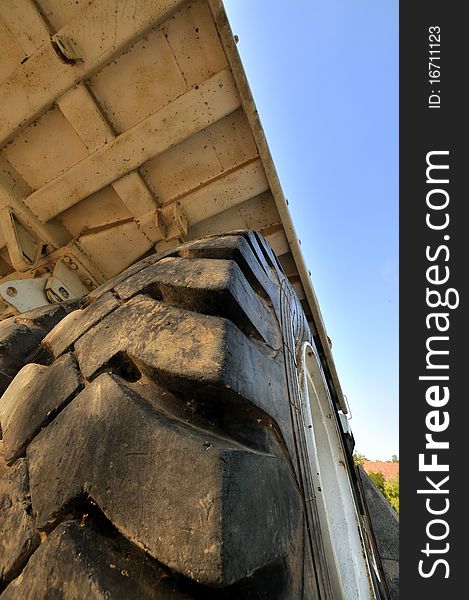 Tyre and body of big loading vehicle under blue sky, shown as working and powerful construct. Tyre and body of big loading vehicle under blue sky, shown as working and powerful construct.