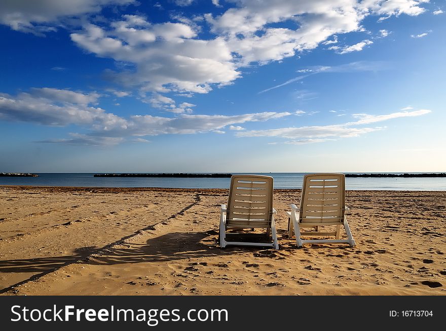 Two abandoned deckchairs in deserted beach. Two abandoned deckchairs in deserted beach