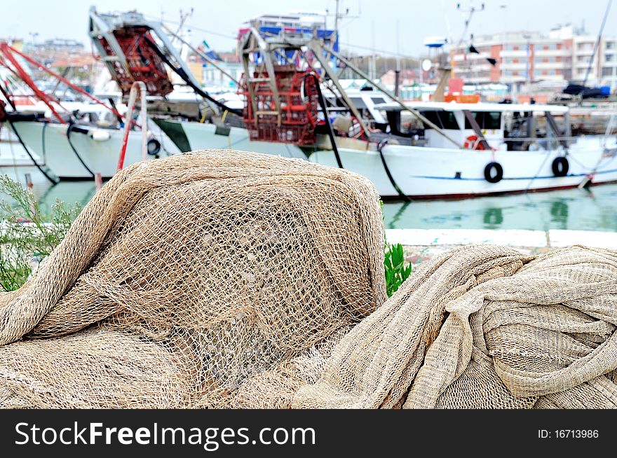 Fishing nets on a harbor's pier with fishing boats in background