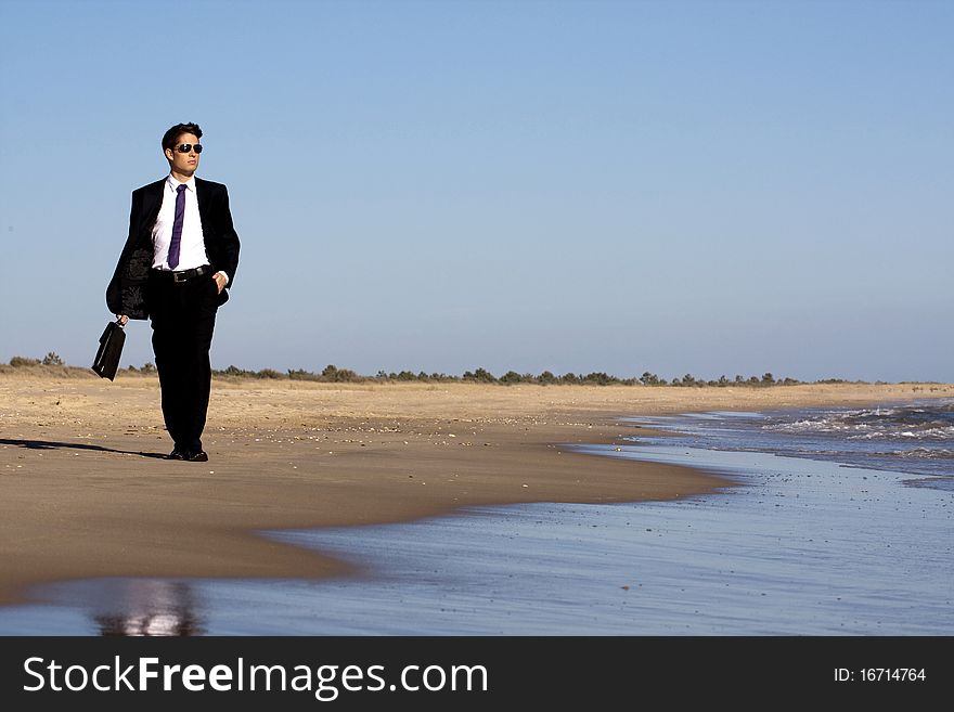 Close up view of a bunisess man in a dark suit walking on the beach. Close up view of a bunisess man in a dark suit walking on the beach.
