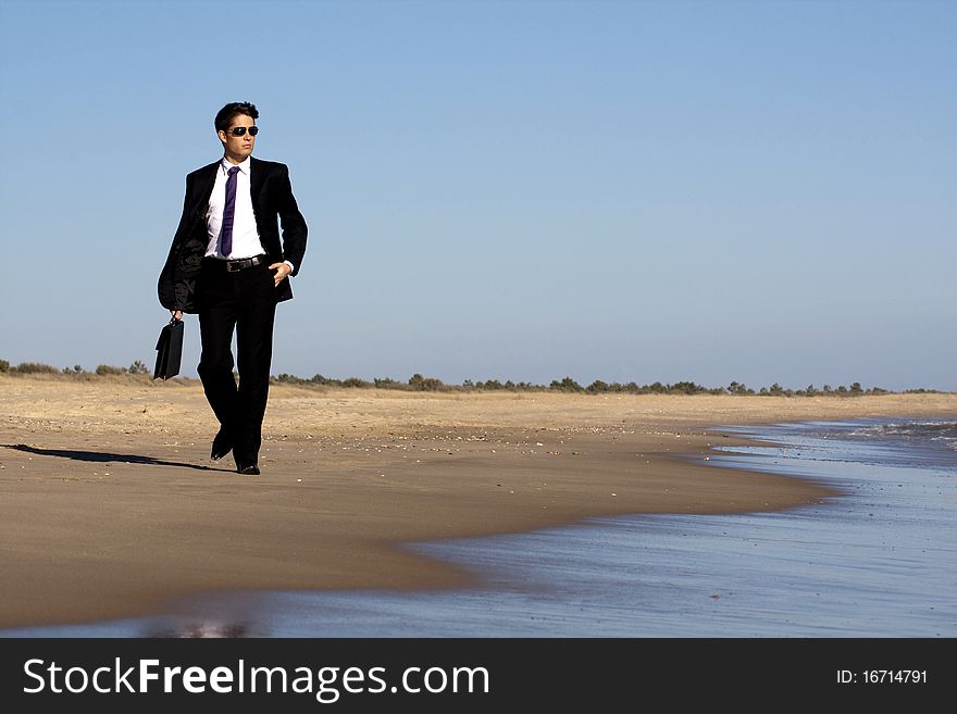 Close up view of a bunisess man in a dark suit walking on the beach. Close up view of a bunisess man in a dark suit walking on the beach.