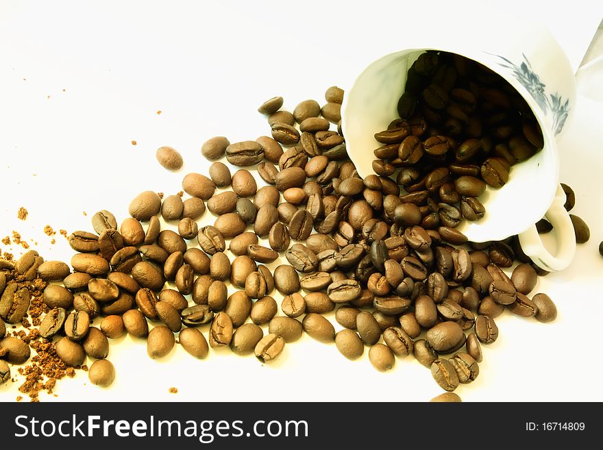 Coffee beans poured from a fine porcelain coffee cup. Coffee beans poured from a fine porcelain coffee cup