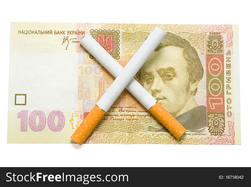 Two cigarettes crossed over one hundred hrivna bil - ukrainian currency. Isolated on white