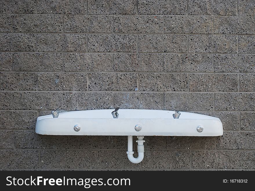 Public drinking fountain on the wall of gray blocks.