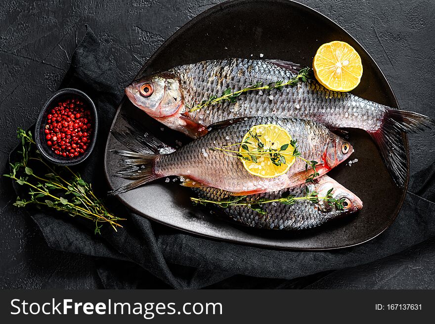 Crucian Carp With Lemon And Thyme On A Black Plate. River Organic Fish. Black Background. Top View