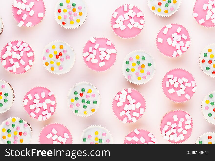 Multiple colorful nicely decorated muffins on a white background, top view. Multiple colorful nicely decorated muffins on a white background, top view