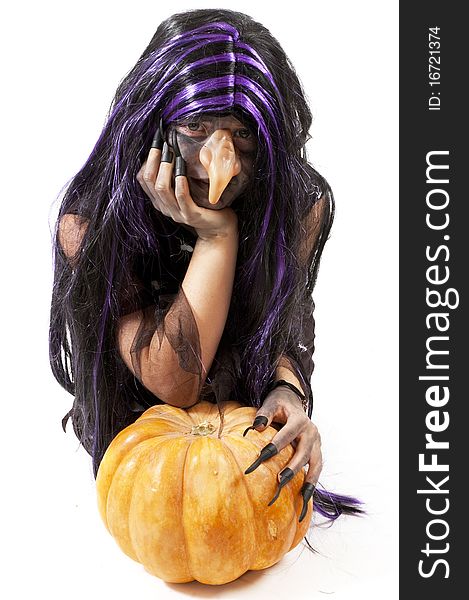 Girl dressed up as a witch leaning on a pumpkin over white