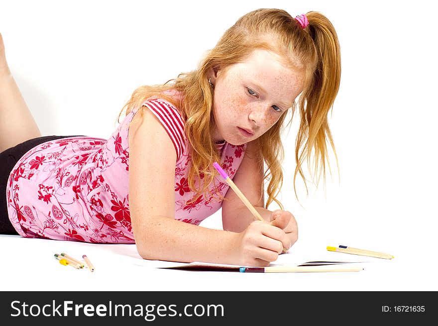 Redhead girl is doing her homework isolated on white