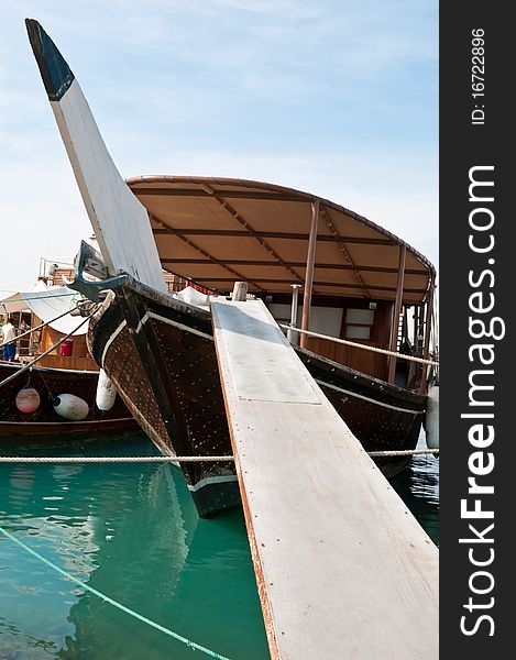 A modern dhow anchored in the bay in Doha, Qatar. The gangway leads the way onto the boat. A modern dhow anchored in the bay in Doha, Qatar. The gangway leads the way onto the boat.