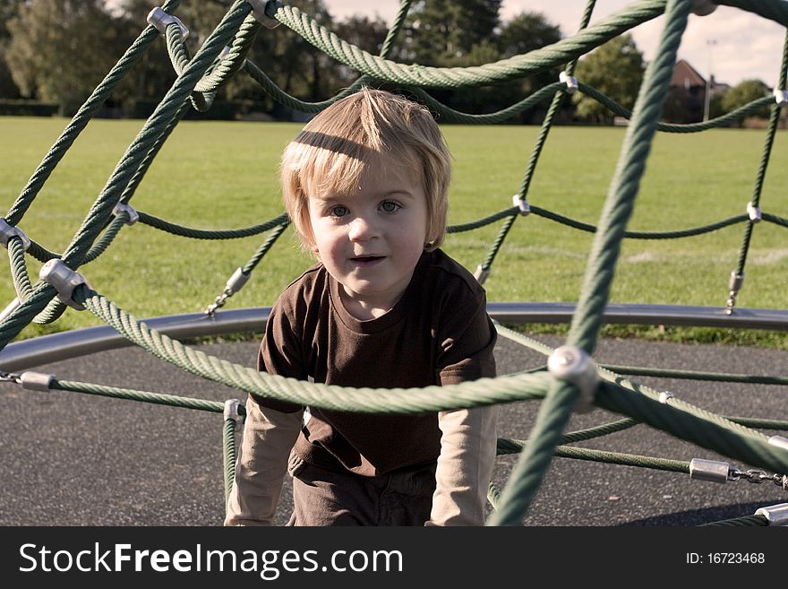 Cute blonde child playing outside in a playground