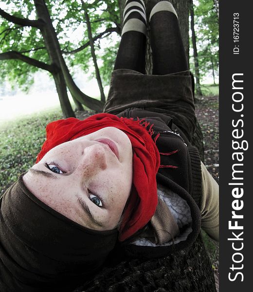 Beautiful girl with red scarf, lying on the branch